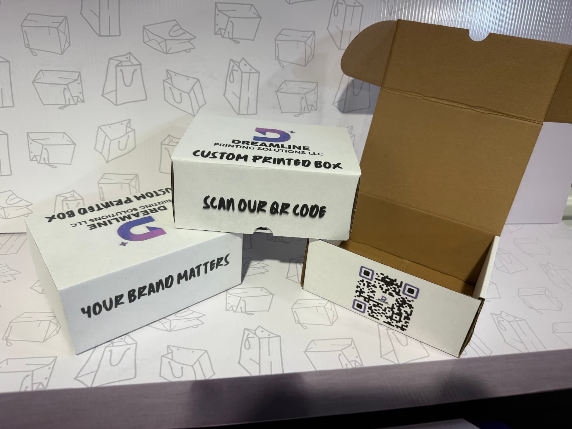 White mailer boxes printed with the Dreamline logo and a QR code